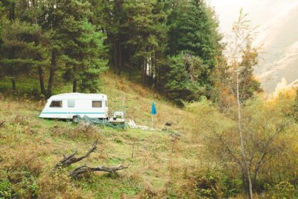 dethleffs wohnwagen - A peaceful forest camping scene with a caravan amidst autumn foliage in the mo