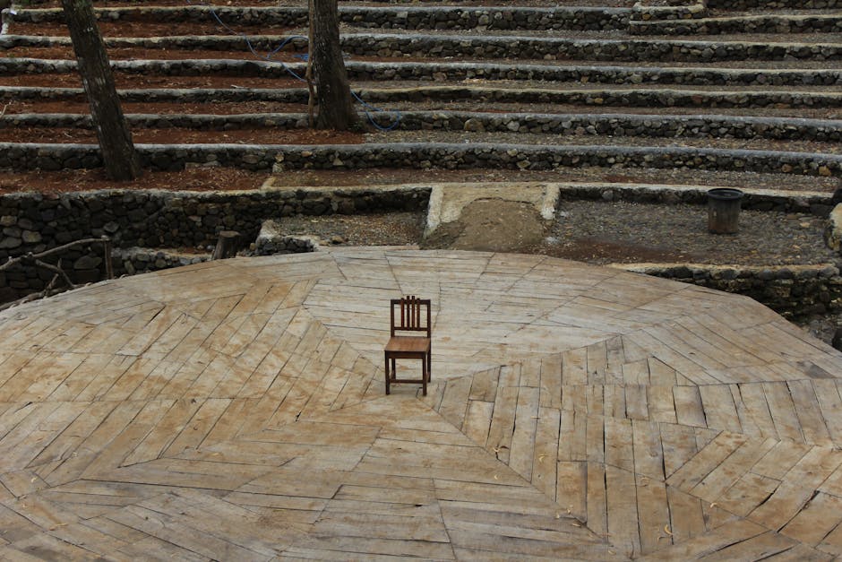 störtebeker festspiele - Lone wooden chair on an amphitheater stage surrounded by trees.